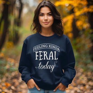 May include: A navy blue sweatshirt with the text "Feeling Kinda Feral Today" in white.