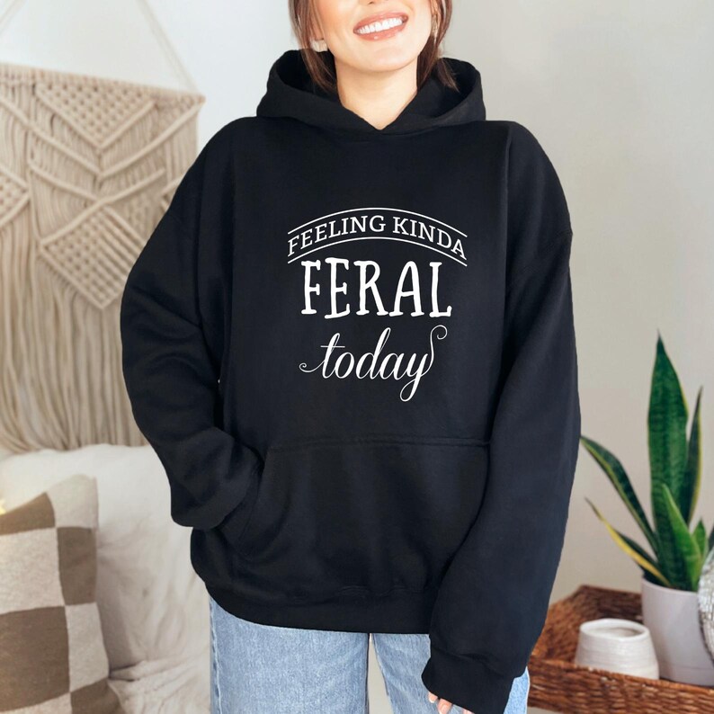 May include: Black hooded sweatshirt with the text "Feeling Kinda Feral Today" in white.