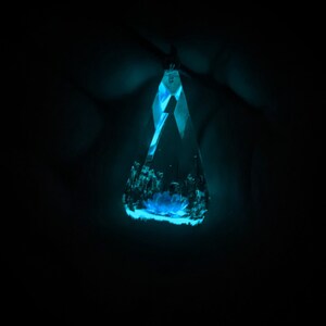 May include: A blue crystal pendant with a faceted design, glowing in the dark.