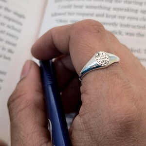 May include: A silver signet ring with a polished finish. The ring features a circular design with the words "I am Enough", a sun, waves, and a mountain illustration. The ring is worn on a finger.