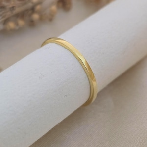 May include: A slender, gold-coloured ring. The ring has a simple, elegant design with a smooth, polished surface. The ring is displayed against a white background.