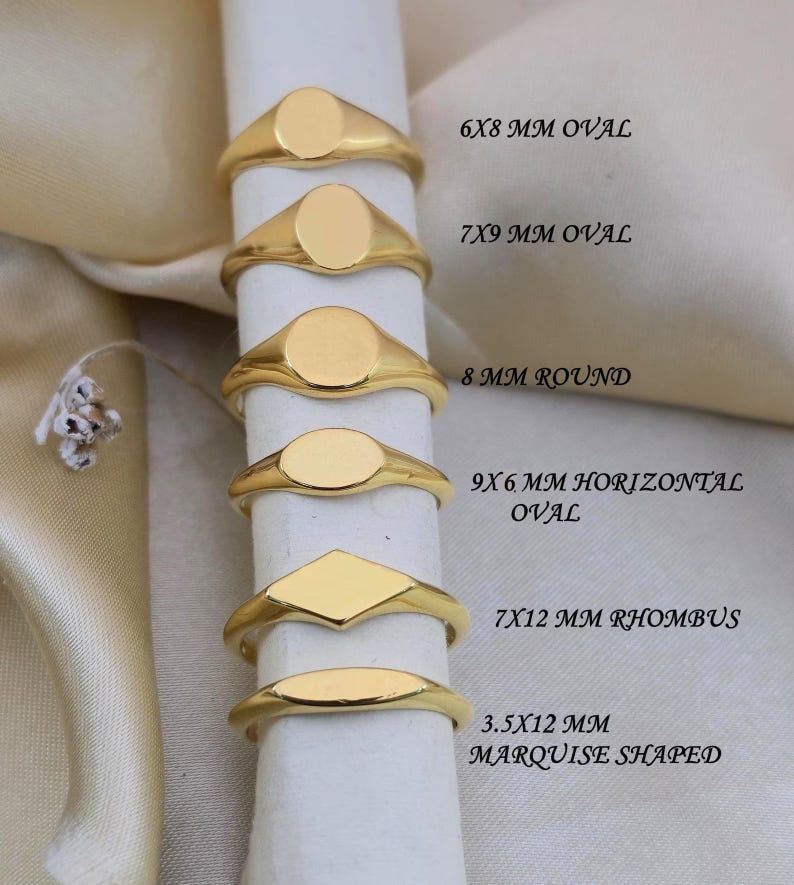 Puede incluir: Una colecci&oacute;n de anillos de sello dorados en varias formas, incluyendo ovalados, redondos y rombos. Cada anillo se muestra con su tama&ntilde;o en mil&iacute;metros, como 6x8 mm ovalado y 7x12 mm rombo. Los anillos se presentan sobre un soporte cil&iacute;ndrico blanco.