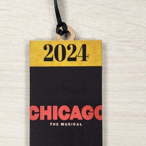 May include: A black and yellow ticket with the text "2024" in yellow and "CHICAGO THE MUSICAL" in red.