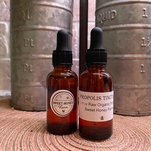 Puede incluir: Dos botellas de vidrio &aacute;mbar con goteros, una etiquetada "Sweet Honey Farm" y la otra etiquetada "Propolis Tincture 1 fl oz Raw Organic Propolis Sweet Honey Farm".
