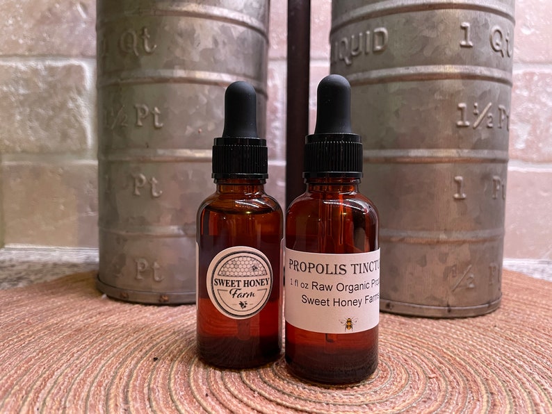 Puede incluir: Dos botellas de vidrio &aacute;mbar con goteros, una etiquetada "Sweet Honey Farm" y la otra etiquetada "Propolis Tincture 1 fl oz Raw Organic Propolis Sweet Honey Farm".