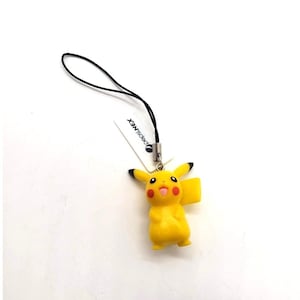 Puede incluir: Figura amarilla de Pikachu con orejas con puntas negras, mejillas rojas y lengua rosa. Adjunta a una cuerda negra y una etiqueta blanca con el texto "pepsi NEX".