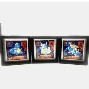 May include: Three framed Pokémon arcade game cards featuring Squirtle, Wartortle, and Blastoise. Each card has a blue background with Japanese text and character illustrations. The frames are black.