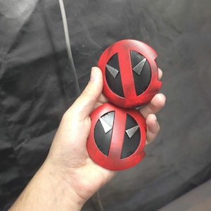 May include: Two red and black round Deadpool logo patches with a distressed paint effect.