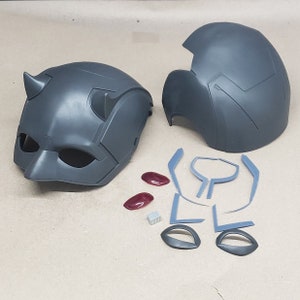 May include: A grey plastic Daredevil helmet with horns, two red eye pieces, and a set of grey plastic pieces for assembly.