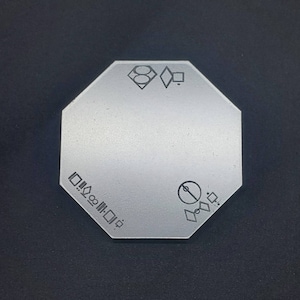 Può includere: Una piastrella ottagonale bianca con disegni geometrici neri. La piastrella ha un cerchio con una linea che lo attraversa, una forma di diamante e il testo "D.O.M.I.N.O."