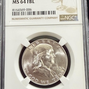 May include: A 1953 D 50C silver coin, graded MS 64 FBL, encased in a protective holder by Numismatic Guaranty Company (NGC). The coin features a profile of a man and the inscription "IN GOD WE TRUST".