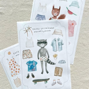 May include: Paper doll sets featuring illustrated animals and clothing. The sets include a raccoon, squirrel, and various outfits, including shirts, shorts, and accessories. The text "DRESS UP FRIENDS" is printed on the top of the paper doll sets.