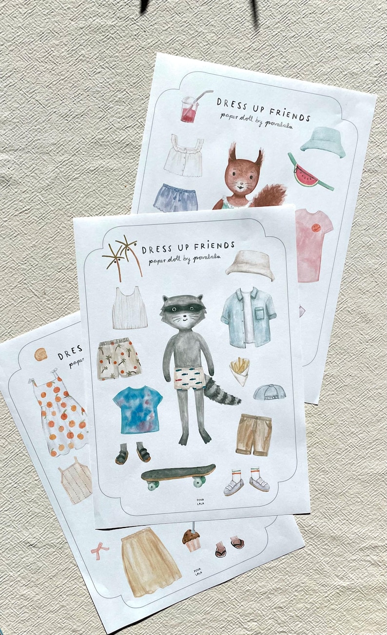 May include: Paper doll sets featuring illustrated animals and clothing. The sets include a raccoon, squirrel, and various outfits, including shirts, shorts, and accessories. The text "DRESS UP FRIENDS" is printed on the top of the paper doll sets.