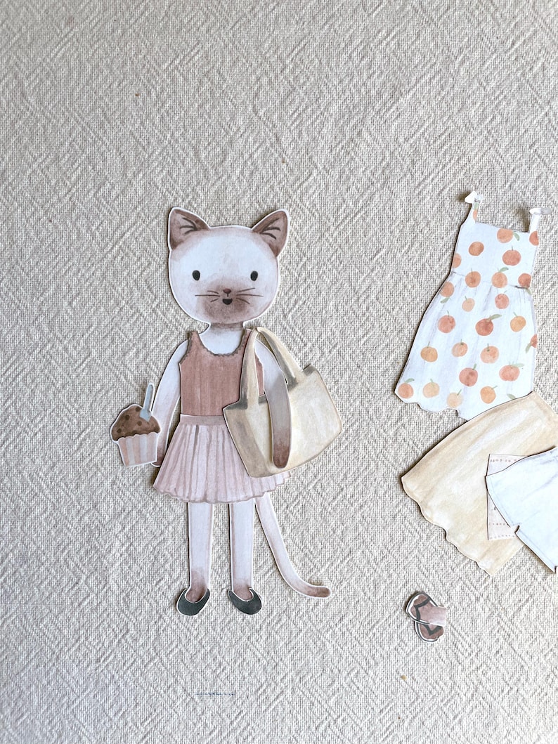 May include: Watercolor illustration of a cat character holding a cupcake and a tote bag, wearing a pink skirt and flats. Additional clothing items include a dress with orange fruit designs, a tan cardigan, and a light blue shirt.