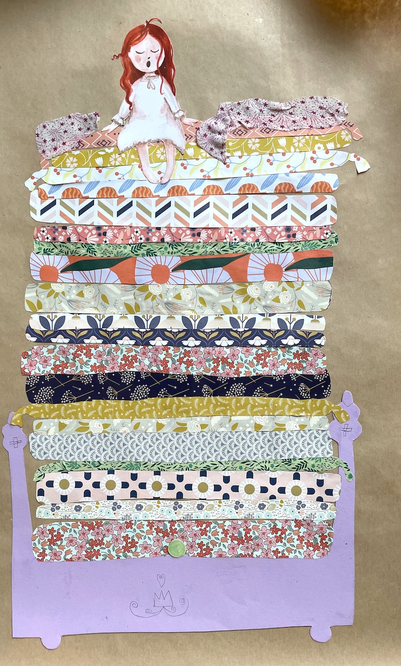 Puede incluir: Una ni&ntilde;a con cabello rojo se sienta encima de una pila de tiras de tela con patrones, que est&aacute;n dispuestas para parecer una cama. La cama es morada y tiene una corona dibujada en la parte inferior.