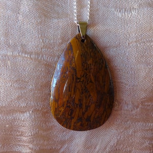 Op de afbeelding: Een druppelvormige ketting met een hanger van bruin en gouden tijgeroog.