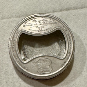 May include: A silver metal jar lid with a pull tab and the text "The Presto Jar and Closure Approved By..." around the edge.