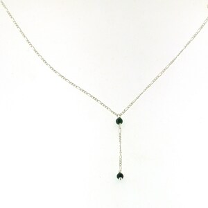May include: A silver chain necklace with two dark green beads hanging from the bottom.