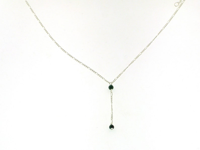 May include: A silver chain necklace with two dark green beads hanging from the bottom.