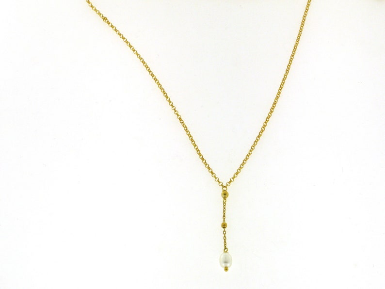 Puede incluir: Un collar de cadena de oro con un colgante de perla &uacute;nico y peque&ntilde;as cuentas doradas.