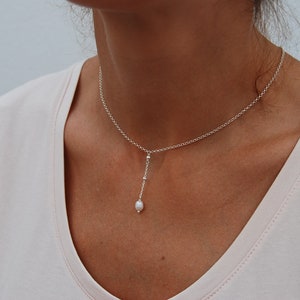 Puede incluir: Un collar de cadena de plata con un solo colgante de perla. El collar es delicado y simple, lo que lo convierte en un accesorio perfecto para el d&iacute;a a d&iacute;a.