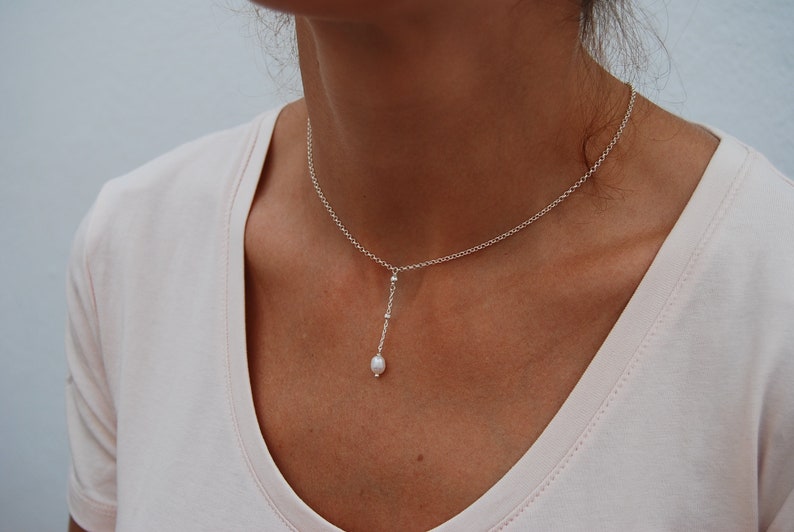 Puede incluir: Un collar de cadena de plata con un solo colgante de perla. El collar es delicado y simple, lo que lo convierte en un accesorio perfecto para el d&iacute;a a d&iacute;a.