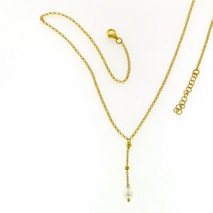 Puede incluir: Un collar de cadena de oro con un colgante de perla &uacute;nico y peque&ntilde;as cuentas doradas.