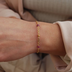 Peut inclure: Un bracelet en chaîne dorée avec de petites perles roses.