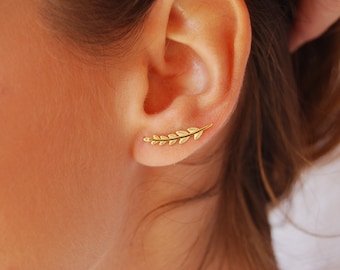 May include: Gold leaf ear cuff earring. The earring is shaped like a delicate branch with small leaves.