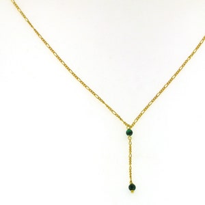 May include: A gold chain necklace with a green stone pendant. The pendant has two green stones.