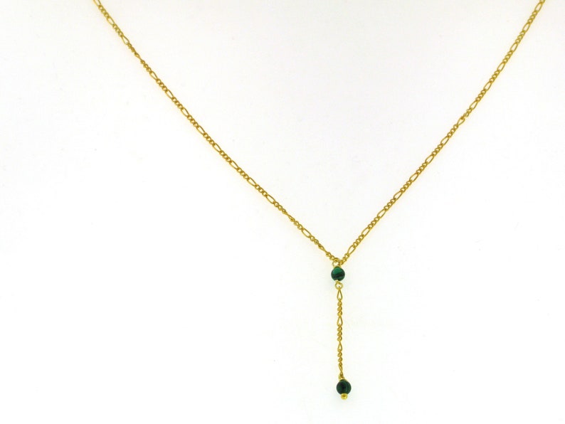 May include: A gold chain necklace with a green stone pendant. The pendant has two green stones.