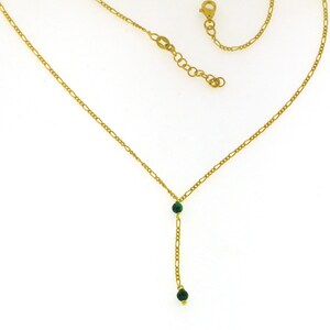 May include: A gold chain necklace with two green gemstone beads.