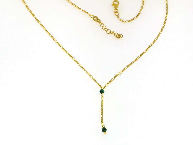 May include: A gold chain necklace with two green gemstone beads.