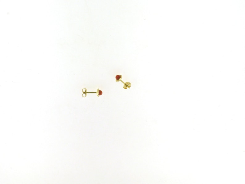May include: A pair of gold stud earrings with small red gemstone accents.