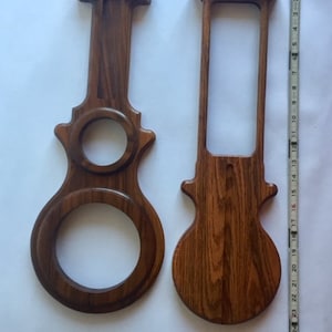 May include: Two wooden decorative pieces with a dark brown finish. One piece has a large circular opening and a smaller one, while the other has a rectangular opening. A ruler is next to the pieces.