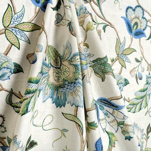 May include: A white fabric with a blue and green floral pattern. The fabric has a subtle sheen and a soft texture.