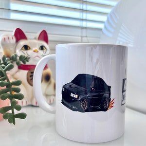 May include: White ceramic mug with a black car illustration and the text "A.I.D.A." printed on the side.