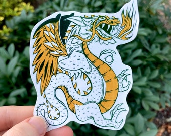 May include: A white and yellow dragon sticker with green wings and a fire tail. The dragon is facing right and has its mouth open.
