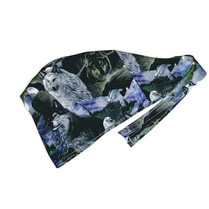May include: A black scrub hat with a colorful print of wolves, eagles, and mountains. The hat has a tie on the back.