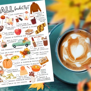 May include: A seasonal bucket list featuring autumn-themed illustrations, such as apple picking, pumpkin pie, and warm sweaters. A coffee cup with latte art sits on a teal saucer, with blurred fall leaves in the background.