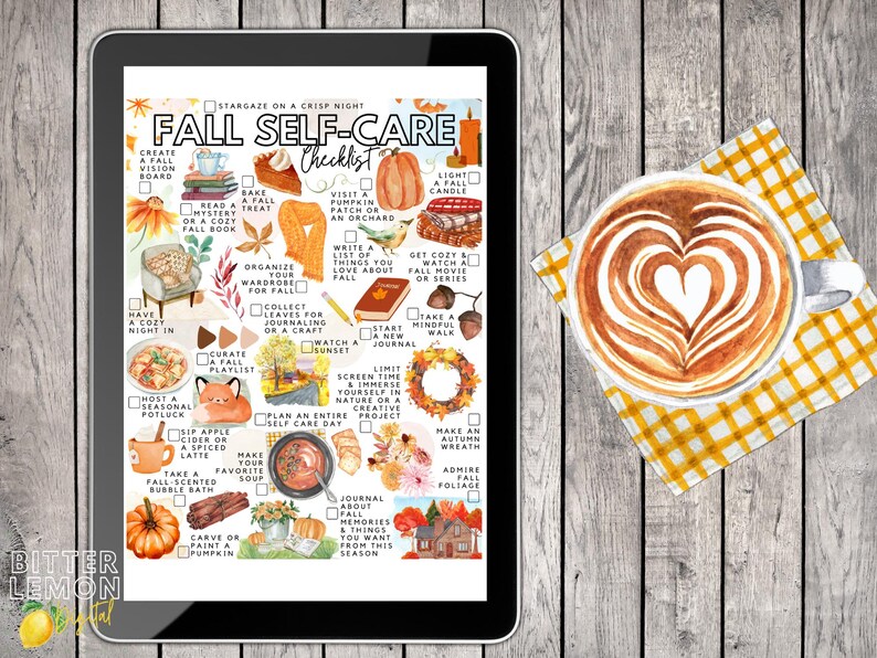 May include: A digital tablet displays a "Fall Self-Care Checklist" with autumn-themed illustrations and text. A latte with heart-shaped foam art sits on a yellow checkered napkin, next to the tablet on a wooden surface.