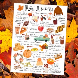 May include: A printed "Fall bucket list" on white paper, with illustrations of autumn activities. The list includes text such as "Visit the Farmer's Market" and "Make a Pumpkin Pie". The background is surrounded by colourful autumn leaves, with a variety of colours.