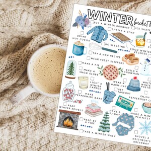 May include: A cozy winter-themed image featuring a white mug of coffee on a cream-colored knitted blanket next to a "Winter Bucket List" checklist. The checklist includes illustrations of winter activities like ice skating, drinking hot cocoa, and building a snowman.