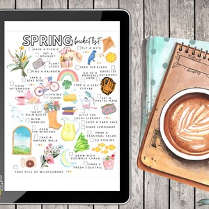 May include: A digital tablet displays a watercolor "Spring Bucket List" with illustrations of spring activities. A notebook with a coffee cup featuring latte art sits beside the tablet on a wooden surface. The tablet's text includes "Bitter Lemon Digital".
