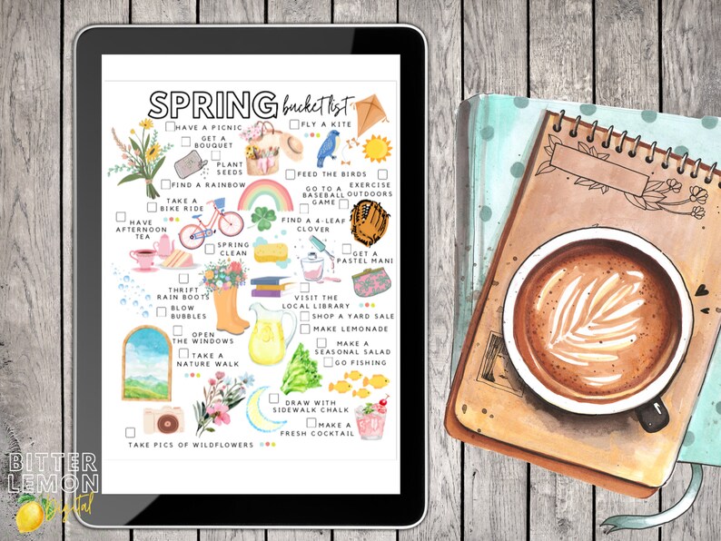 May include: A digital tablet displays a watercolor "Spring Bucket List" with illustrations of spring activities. A notebook with a coffee cup featuring latte art sits beside the tablet on a wooden surface. The tablet's text includes "Bitter Lemon Digital".