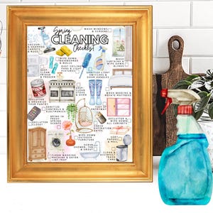 May include: A gold-framed print featuring a Spring Cleaning Checklist with various household chore illustrations and text, including vacuuming, dusting, and organising tasks, displayed alongside a blue liquid spray bottle.