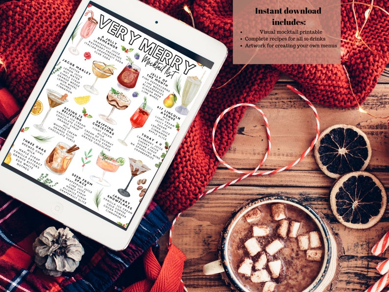 K&ouml;nnte beinhalten: Ein Tablet zeigt eine "Very Merry Mocktail List" mit Getr&auml;nkeillustrationen und Rezepten. Es liegt auf einer Holzoberfl&auml;che mit einer roten Strickdecke, getrockneten Orangenscheiben und einer Tasse hei&szlig;er Schokolade.