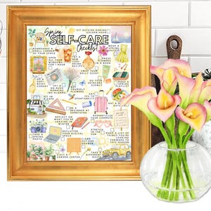 May include: A framed print with a gold border displays a watercolour "Spring Self-Care Checklist." The print is next to a vase of pink calla lilies. The checklist includes ideas like "Open all your windows" and "Take a spring photo."