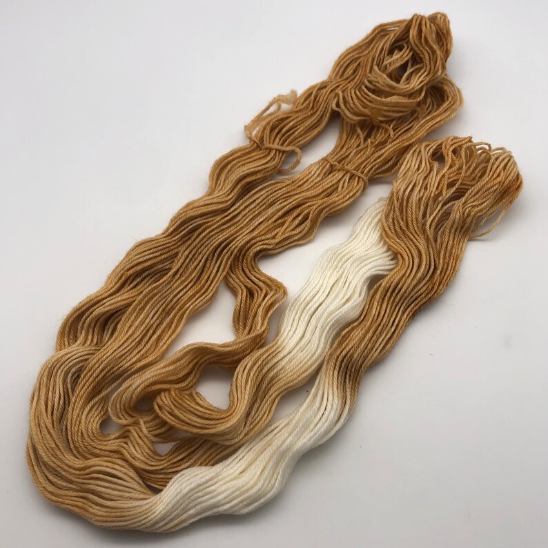 May include: Two skeins of yarn, one white and one ombre from white to brown.