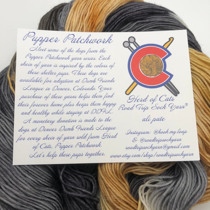 May include: A close-up of a skein of yarn in three colors: gray, tan, and brown. The yarn is labeled "Pupper Patchwork" and "Herd of Cats Road Trip Sock Yarn." The label also includes information about the yarn's purpose and how to purchase it.